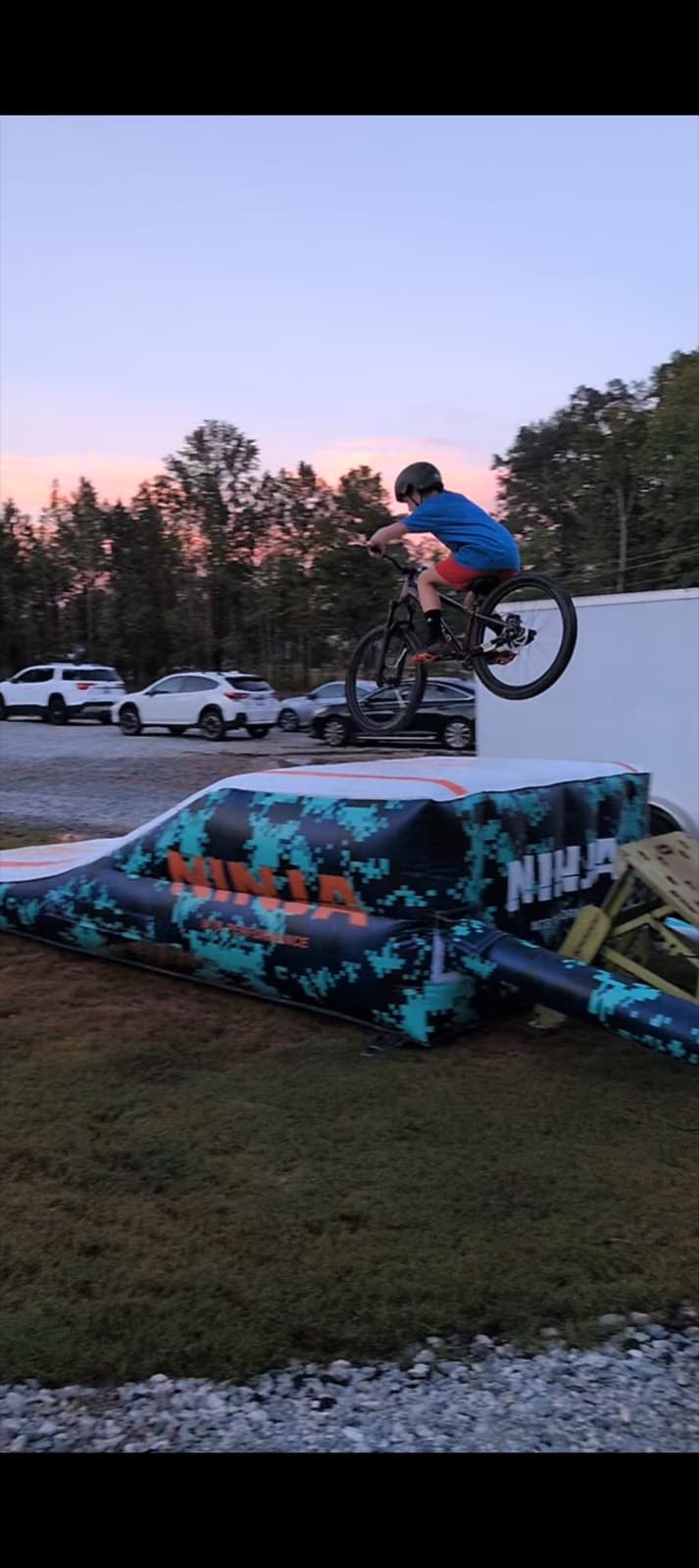 Youth rider catching air onto the portable air bag at dusk